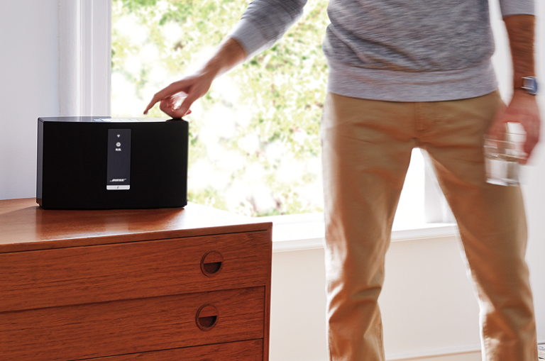 A man using the Bose SoundTouch 20 speaker on a living room sideboard