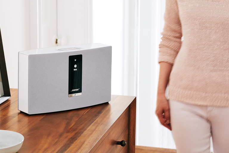 A woamn walks by the Bose SoundTouch 20 Wireless Music System on a living room table