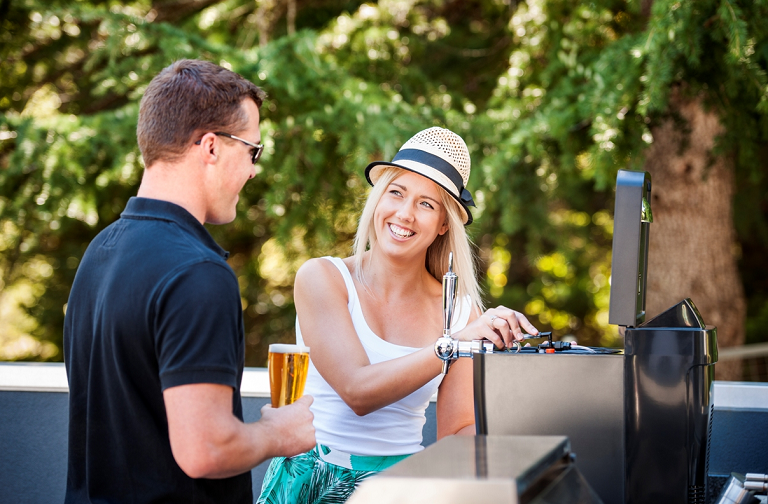 A man and woman beside a BBQ, pouring drinks from the BrewFlo keg