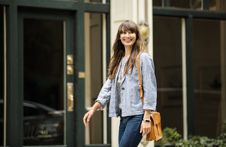 A woman wearing a Fitbit Alta and smiling
brightly as she walks.