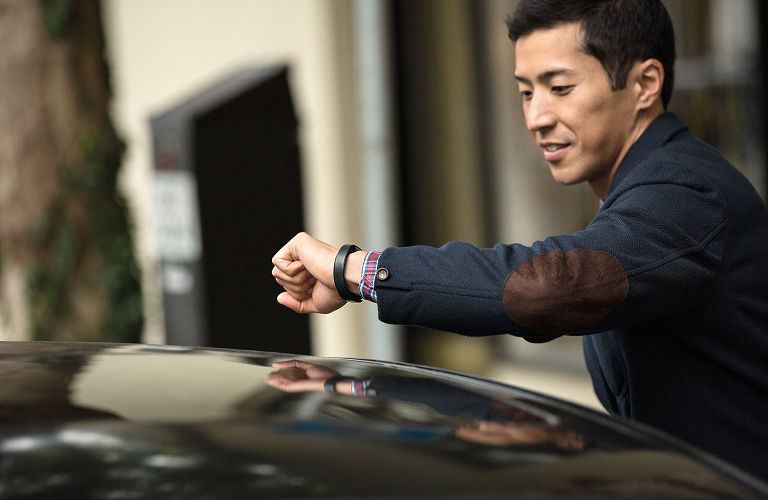 A man checking his Fitbit Alta as he gets into
his car.