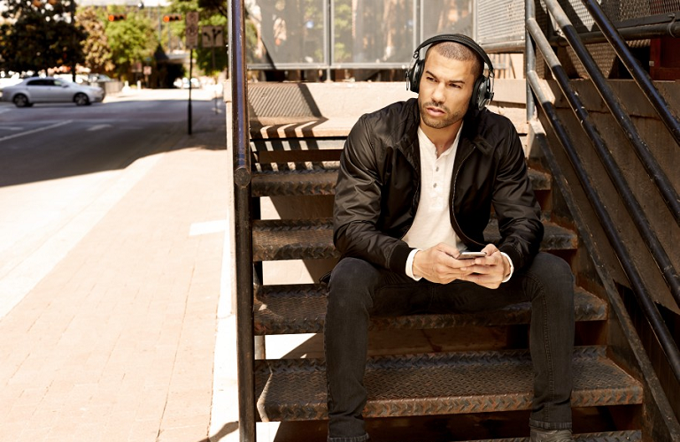 A man sitting on stairs outside
wearing Momentum Wireless Headphones.
