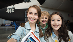 Three children holding a device showing Office 365 Powerpoint.