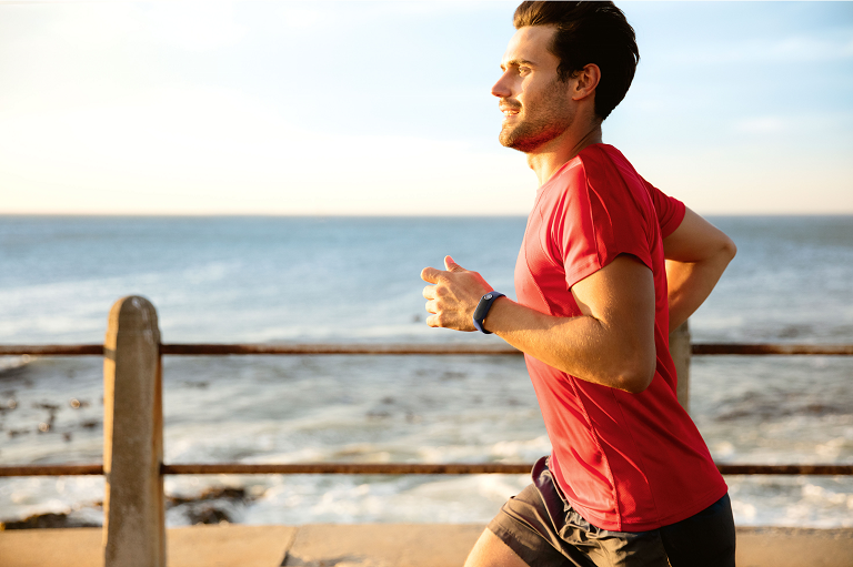 A man running on the beach wearing the TomTom fitness tracker