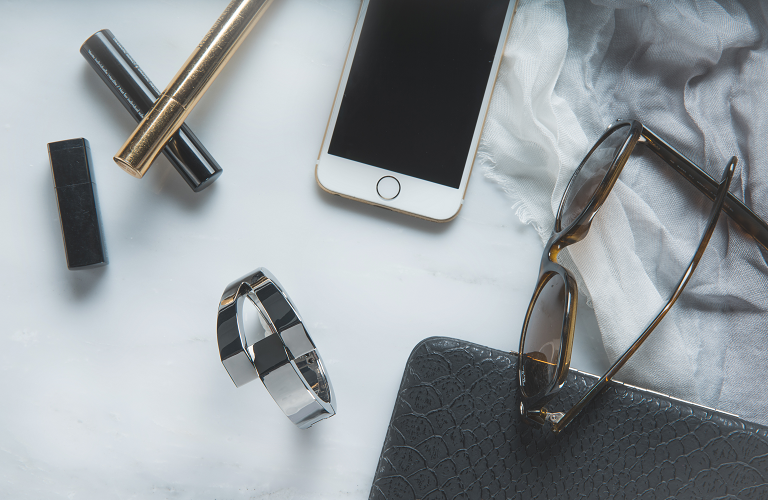 A Wisewear activity tracker beside
everyday items such as a phone, sunglasses and lipstick.